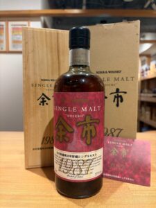 Nikka Whisky Yoichi single malt bottle with red label beside its wooden box