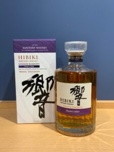 BAoSJwDAZlukMsWo2IHbkikq24AywZa5kPzbvUox お酒買取専門店LIQUORJOYリカージョイ Bottle of Hibiki Japanese Harmony Masters Select whiskey beside its purple and white box on a wooden surface blue wall behind