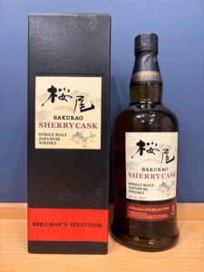 Bottle of SakurAO Sherry Cask Japanese whisky beside its black box both labeled Stillmans Selection on a wooden surface