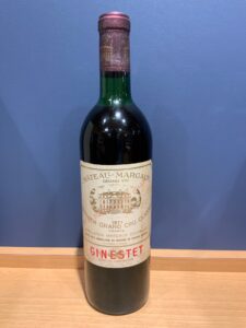 lEyRNjuI3qluuQX2TJFliJRUEKeyrmHpqRXDyHjX お酒買取専門店LIQUORJOYリカージョイ Tall dark wine bottle with a cream label showing a chateau illustration and the text Château Margaux Grand Vin 1971 against a blue wall