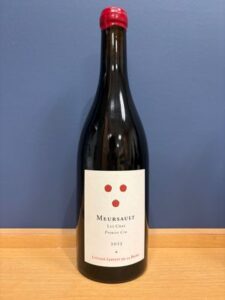 sm2 お酒買取専門店LIQUORJOYリカージョイ Wine bottle with red capsule on a wooden surface against a blue wall label reads Meursault Les Clos Premier Cru 2013